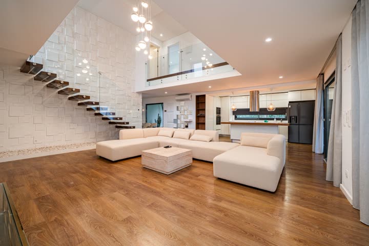 Interior de uma moradia com sala, escada e pavimento em madeira